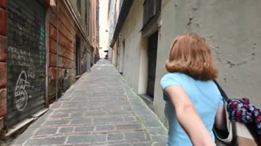 Cenova, Liguria, İtalya. 3 Haziran 2023. Tarihi merkezin ara sokaklarında yürürken, orta yaşlı bir kadın elimizi tutup bize yol gösteriyor. Beni takip et..