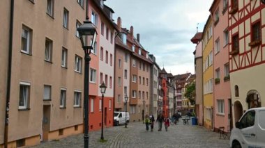 Nuremberg, Almanya, 1 Ağustos 2023. Tanner 'ların sokağı: Eski şehrin tüm cazibesine sahip renkli ve yarı keresteli evlerin cephelerine sahip. İnsanlar taş kaplı cadde boyunca yürür.