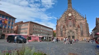 Nuremberg, Almanya, 1 Ağustos 2023. Bir yaz gününde pazar meydanının güzel manzarası. Güzel kilise bulutlu mavi gökyüzüne karşı duruyor. İnsanlar meydanda yürüyor. Eğim hareketi.