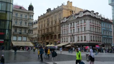 Prag, Çek Cumhuriyeti, 4 Ağustos 2023. İnsanlar yağmurlu günlere rağmen tarihi merkezden geçiyorlar. Şemsiyeli insanlar her yöne yürür. Renkli yüzlü güzel binalar.