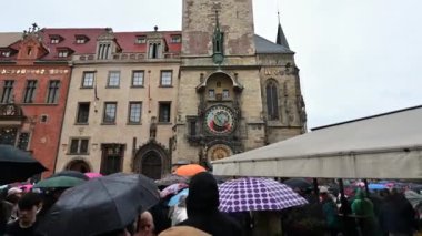 Prag, Çek Cumhuriyeti, 4 Ağustos 2023. Güzel astronomik saatin önünde toplanan kalabalığın görüntüsü, yağmurlu bir günde atlıkarıncanın zamanı gelmesini beklemesine rağmen..