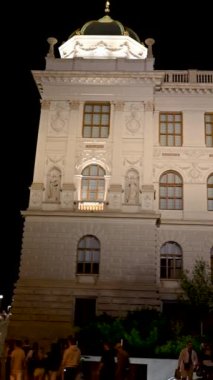 Prag, Çek Cumhuriyeti, 4 Ağustos 2023. Ulusal müzeye ev sahipliği yapan binanın gece görüntüsü dikey formatta. İnsanlar akşam yürüyüşüne çıkar..
