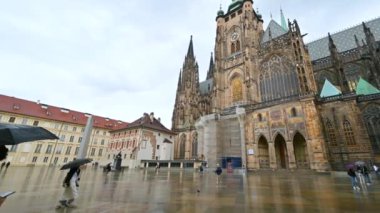 Prag, Çek Cumhuriyeti, 4 Ağustos 2023. San Vito Katedral Meydanı 'nın yağmurlu bir günündeki görüntüler. Pan hareketi, şemsiyeli insanlar.