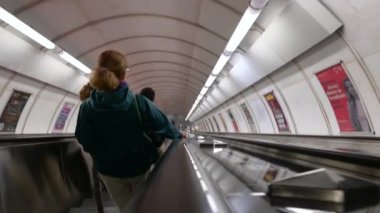 Prag, Çek Cumhuriyeti, 4 Ağustos 2023. Metrodaki yürüyen merdivenlerdeki görüntüler çalıştırılıyor. Önümüzde orta yaşlı bir kadın ve iki genç Kafkasyalı..