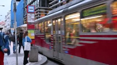 Prag, Çek Cumhuriyeti, 4 Ağustos 2023. Tramvay durağındaki şehir merkezinde, klasik bir model geçiyor ve ardından modern bir tramvay duruyor, insanlar kaldırımda bekliyor..