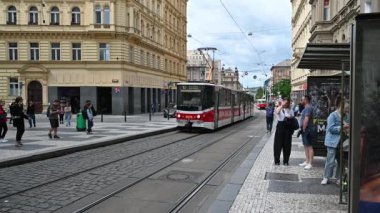 Prag, Çek Cumhuriyeti, 4 Ağustos 2023. Tramvay durağında yavaş çekim, 10. hat, kırmızı ve beyaz tramvay durağa yaklaşırken insanlar trene yaklaşır..
