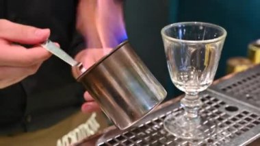 Prag, Çek Cumhuriyeti, 4 Ağustos 2023. Absinthe 'in hazırlanmasıyla muhteşem görüntüler. Barmen, çay kaşığındaki şeker küpünü alkollü alevle ustalıkla karamelize ediyor..