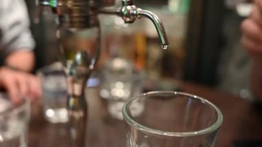 Prag, Çek Cumhuriyeti, 4 Ağustos 2023. Absinthe 'in eski bir kasaba barına damlaya damlaya damlaya sallaya sürahide servis edilen büyüleyici yavaş çekim görüntüleri. Musluğa yakın çekim yap..