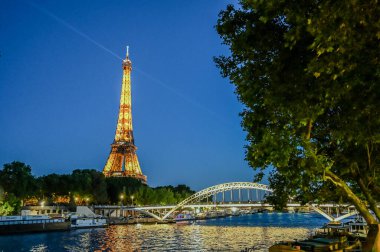 Paris, Fransa, 1 Temmuz 2022. Eyfel Kulesi 'nin mavi saatindeki ikonik görüntüsü Seine Nehri' ni ve nehir boyunca uzanan kulüpleri çevrelemektedir. Gece hayatı, dönüm noktaları.