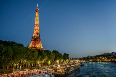 Paris, Fransa, 1 Temmuz 2022. Eyfel Kulesi 'nin mavi saatindeki ikonik görüntüsü Seine Nehri' ni ve nehir boyunca uzanan kulüpleri çevrelemektedir. Gece hayatı, dönüm noktaları.