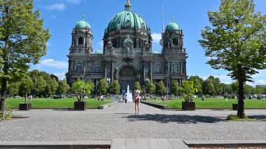 Berlin, Almanya, 16 Ağustos 2023. Katedral cephesinde cep telefonuyla fotoğrafını çeken bir kadınla güzel görüntüler. Güzel bir yaz günü, eğik hareket.