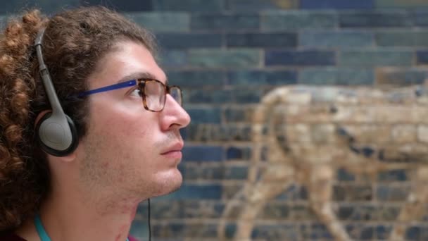 2023年8月16日 德国柏林 柏林Pergamon博物馆的Ishtar门 一个留着卷发和眼镜的年轻的高加索人在忙着聆听带耳机的音频向导的画像 — 图库视频影像