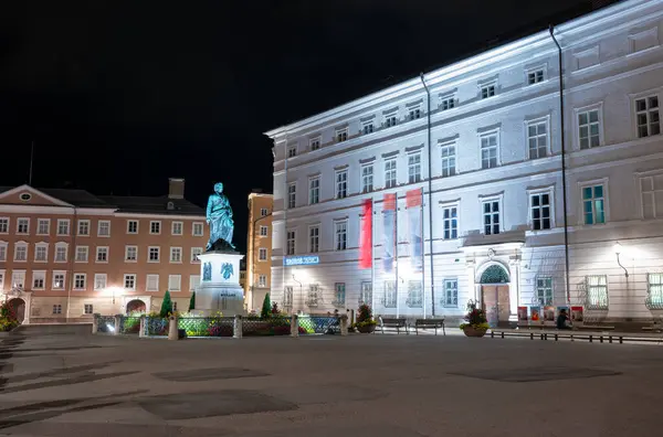 Salzburg, Avusturya, 15 Ağustos 2022. Mozart Meydanı 'nda büyüleyici bir gece çekimi. Mozart heykelinin sağında şehir müzesi var..