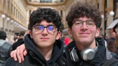 Milan, Lombardy, İtalya. 1 Nisan 2024. Vittorio Emanuele II galerisinde poz veren iki beyaz gencin portresi kalabalık. Etrafa bakınıp surat asıyorlar..