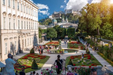 Salzburg, Avusturya, 15 Ağustos 2022. Mirabell Palace Gardens 'ın büyüleyici gündüz çekimi. İnsanlar onları ziyaret eder ve keşfederler. Arka planda Hohensalzburg kalesi ön plana çıkıyor..