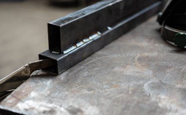 İşteki kavramsal görüntü: bir atölyede iki metal çubuğun kaynak noktası üzerine seçici odaklanma. Çalışma konsepti, metal işçiliği, onarım, yaratıcılık.