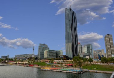 Viyana, Avusturya, 17 Ağustos 2022. Tuna Nehri manzarası ve Viyana DC olarak da bilinen Donau City, sağ tarafta DC Kulesi 'ni aydınlatıyor..