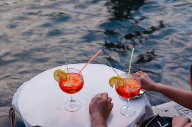 Bir çift deniz kenarında iki bardak spritz ile aperatiflerinin tadını çıkarıyor. Boşluğu kopyala.