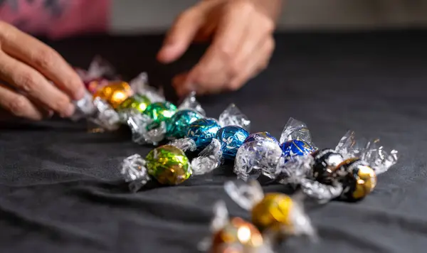 stock image Vienna, Austria August 20, 2022. Beautiful image with group of Lindt Lindor chocolates, different shapes in multicolored wrappers. A hand in the background grabs one. Concept of relaxation, pampering.