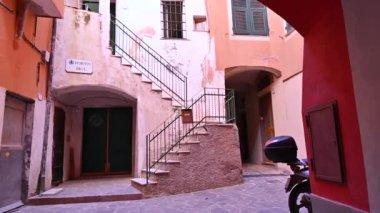 Laigueglia, İtalya, 14 Temmuz 2024. Tarihi merkezi araştıran güzel yavaş çekim POV görüntüleri: üst kata çıkan dış merdivenlerle karakteristik bir avluda ilerliyoruz..