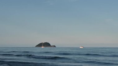 Alassio, Liguria, İtalya. Deniz ufkunda Gallinara Adası 'nın hatları aşikar. Bir çift tekne..