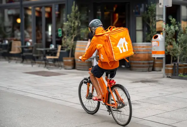 stock image Vienna, Austria, August 23, 2022. A rider from Lieferando, home delivery company for food and drink. It is easy to notice them: the showy orange duffel bag with the typical white logo.