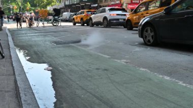 New York, ABD, 14 Ağustos 2024. Şehrin ikonik bir görüntüsü: buharlı bir rögar deliği. Karakteristik sarı taksiler trafik ışıklarında durdu. İnsanlar yaya geçidini geçiyor..