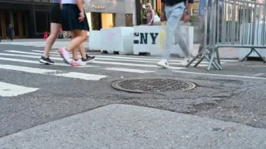 New York, ABD, 14 Ağustos 2024. Şehrin ikonik bir görüntüsü: içinden buhar çıkan bir rögar kapağı. Arka planda New York Polisi yazıyor. İnsanlar yaya geçidinden karşıya geçiyor..