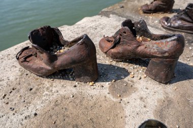 Budapeşte, Macaristan. 25 Ağustos 2022. Nazi baskısının kurbanlarının anısına. Tuna Nehri seti üzerindeki eski ayakkabıların paslı metal kopyaları. Soykırım ve Nazi terör hafızası kavramı.