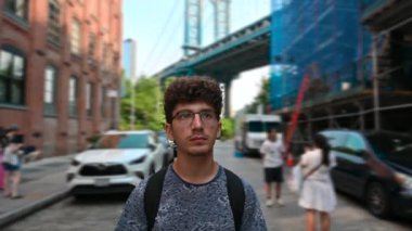 New York, Birleşik Devletler, 15 Ağustos 2024. Dumbo, şehrin ikonik görüntüsü. Genç bir adam caddede yürürken arkasında Manhattan Köprüsü manzaralı bulanık bir arka plan vardı. İnsanlar.