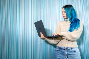 Dizüstü bilgisayarla çalışan, klavyede yazan güzel mavi saçlı hippi kadın portresi. Sorun çözme, pozitiflik ve başarı.