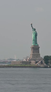 New York, ABD, 16 Ağustos 2024. Tekneyle yanından geçerken Özgürlük Anıtı manzaralı büyüleyici dikey görüntüler. Turistler adada gezmek için görülebilir..