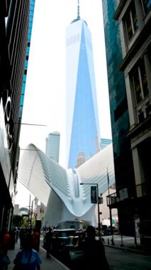 New York, ABD, 16 Ağustos 2024. Fütürist Oculus İstasyonu 'nu ve Özgürlük Kulesi' ni çevreleyen sokak manzaralı güzel dikey görüntüler. İnsanlar ve arabalar gelip gidiyor. Şehrin ikonik görüntüleri.