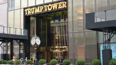 New York, ABD, 17 Ağustos 2024. Beşinci Cadde 'deki Trump Tower' ın girişi. Ayırt edici klasik saat ve altın sarısı tabela göze çarpıyor. İki adam girişi tutun..