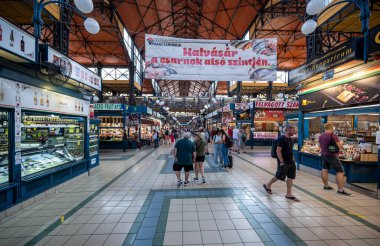 Budapeşte, Macaristan. 29 Ağustos 2022. Kapalı pazar: insanlar satıcılar tarafından sergilenen malları izlemek için merkez koridoru dolduruyorlar.