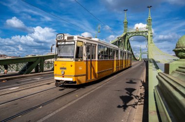 Budapeşte, Macaristan, 29 Ağustos 2022. Güzel bir yaz gününde, Liberty Köprüsü manzarası toplu taşıma hizmetinin klasik tramvaylarından biriyle kesişiyor. Şehrin ikonik görüntüleri.