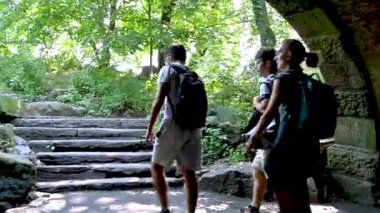 New York, ABD, 18 Ağustos 2024. Central Park 'ı keşfederken, üç kişilik küçük bir grup küçük bir tünelden çıkar ve ağaçların arasındaki patikaya doğru yürürler..