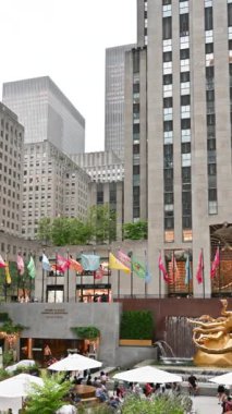 New York, ABD, 18 Ağustos 2024. Rockefeller Center 'ın görüntüleri, şehir hayatının buluşma noktası. Masalarda şemsiyeli insanlar, alışveriş merkezini ziyaret edenler. Seyahat yerleri. Dikey biçim.