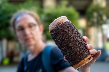 Budapeşte, Macaristan, 30 Ağustos 2022. Çikolatalı pralinlerle süslenmiş, orta yaşlı bir kadının uzanmış kolu tarafından tutulan ve tadına bakmadan önce bunu gösteren bir baca pastasının yakın çekimi. Sokak yemekleri yaşam tarzı