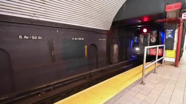 New York City, ABD, 20 Ağustos 2024. Metro platformunda yavaş çekim. Tren geliyor, parlak metal ve Amerikan bayrağı belirgin bir şekilde sergileniyor..