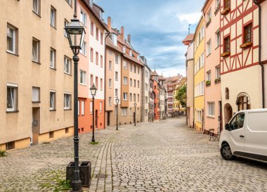 Nuremberg, Almanya, 1 Ağustos 2023. Tanner 'ların sokağı: Eski şehrin tüm cazibesine sahip renkli ve yarı keresteli evlerin cephelerine sahip. İnsanlar taş kaplı cadde boyunca yürür.