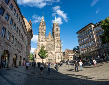 Nuremberg, Almanya, 1 Ağustos 2023. Güneşli bir günde St. Lorenz Kilisesi 'nin güzel bir fotoğrafı. Beyaz bulutlar mavi gökyüzünü geçiyor, insanlar kilisenin önünde yürüyor. Büyük biçim görüntüsü.