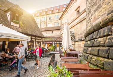 Nuremberg, Almanya, 1 Ağustos 2023. Tarihi şehir duvarları içinde, antik dükkanların zarif bir yeniden inşası artık restoranlara ve barlara ev sahipliği yapıyor. İnsanlar yürüyor ve masalara oturuyorlar. Şehir hayatı.