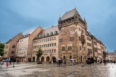 Nuremberg, Almanya, 2 Ağustos 2023. Şehrin en ikonik manzaralarından birinin yağmurlu bir günü. St. Lawrence Kilisesi 'nin önünde muhteşem bir mimari örneği var. Şemsiyeli insanlar.