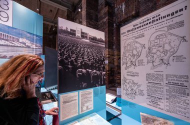 Nuremberg, Almanya, 3 Ağustos 2023. Terk edilmiş Nazi Kongre Sarayı 'ndaki belge merkezinde orta yaşlı bir ziyaretçi bilgi panellerini okuyor. Seyahat yerleri.