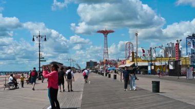 New York City, ABD, 21 Ağustos 2024. POV görüntüleri, Coney Adası 'ndaki sahil yolunda yürüme görüntüleri, arka planda lunapark gezintileri. İnsanların yanından geçiyoruz. Güzel bir yaz günü. Seyahat yerleri.