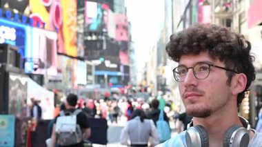 New York City, ABD, 22 Ağustos 2024 kıvırcık saçlı ve gözlüklü beyaz bir adam Broadway ve Times Meydanı 'nın bulanık arka planına karşı selfie çekiyor. Teknolojiyi kullanan bir şehir yaşam tarzı.