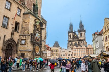 Prag, Çek Cumhuriyeti, 5 Ağustos 2023. Astronomik saat ve arka planda Tyn Hanımefendisi Kilisesi 'nin olduğu meydanın ikonik görüntüsü. Kalabalık, yağmurlu gökyüzü. Seyahat yerleri.