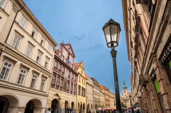 Prag, Çek Cumhuriyeti, 5 Ağustos 2023. Arka planda gıda pazarı ve St. Havel Kilisesi var. Renkli cepheli güzel ortaçağ evleri sokağa bakıyor. İnsanlar pazarda geziniyor..