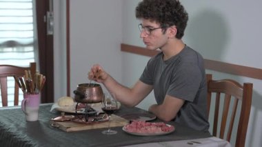 Kıvırcık saçlı ve gözlüklü beyaz bir adamın görüntüsü. O bir masada oturuyor, yanında bir bardak şarap ve bir burginyon hazırlıyor. Lezzetli yemeklerle damgalanmış bir yaşam tarzı..